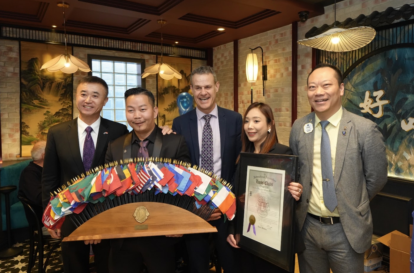 Club representatives and guests gathered with the Lions international friendship display